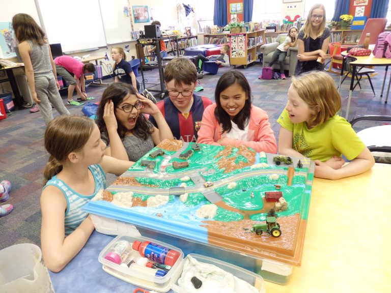 Students looking at model of watershed in classroom